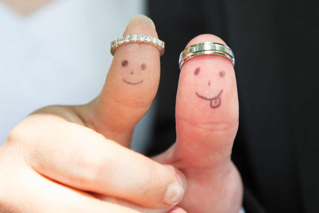 newlyweds displaying thumbs with wedding rings and smiley faces