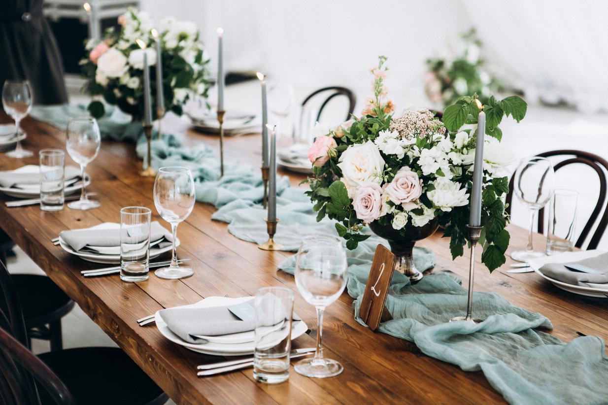 Wedding reception tablescape with a blue table runner, candles, and pink bouquets