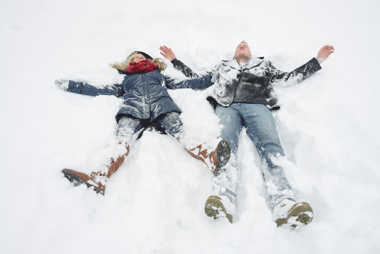 Cute couple making snow angels in winter shoot by Amy Aiello Photography