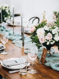 Wedding reception tablescape with a blue table runner, candles, and pink bouquets