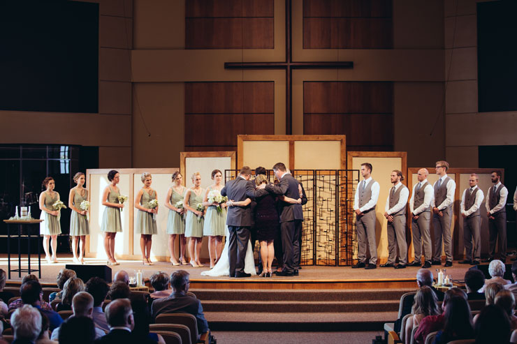 Parents praying together with Kyle and Natalie during their church wedding ceremony