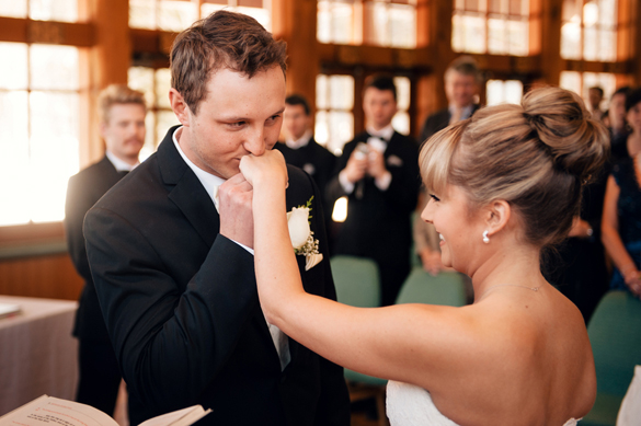 Groom kissing bride's hand during wedding ceremony