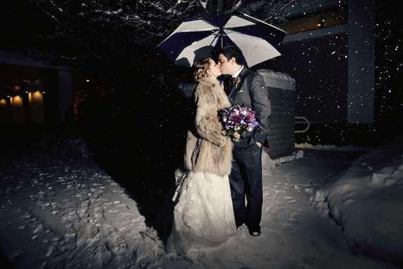 bride and groom outside in winter wedding under an umbrella at night