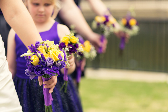 bridesmaids lined up holding purple and yellow wedding bouquets
