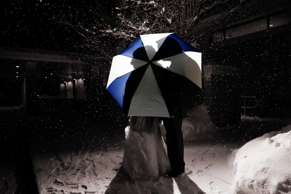 sihlouette of bride and groom kissing behind umbrella
