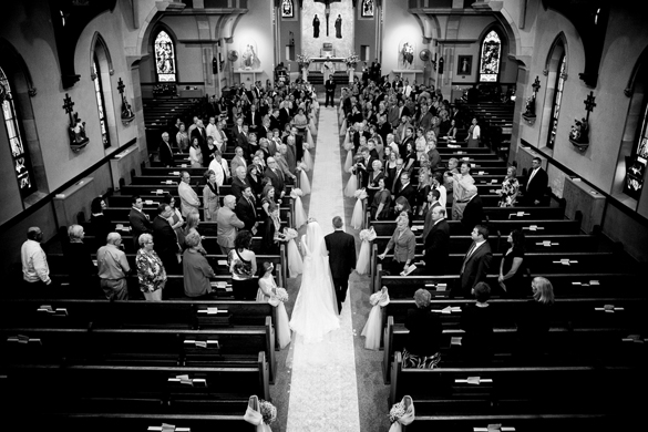 black and white wedding photo of bride walking down the aisle