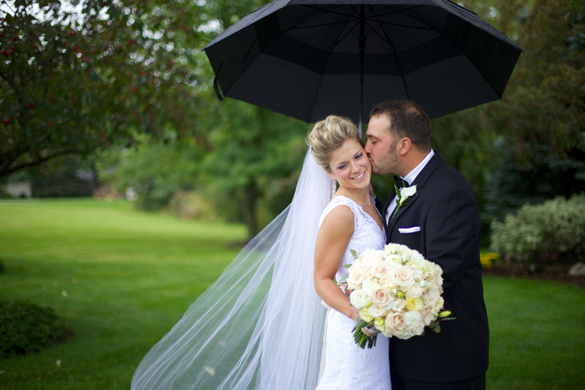 outdoor wedding photo of bride and groom holding a black umbrella