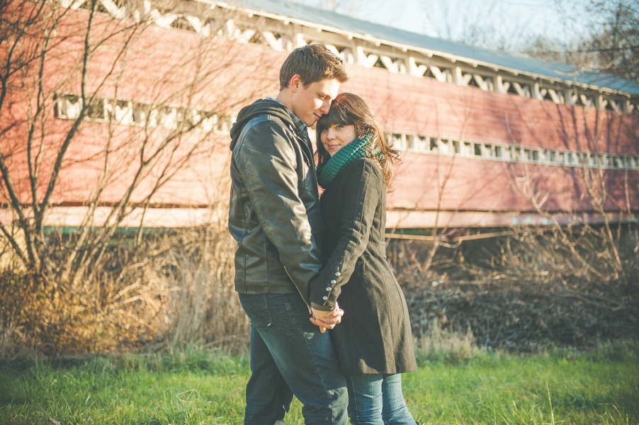 Rustic fall engagement photo by a covered bridge
