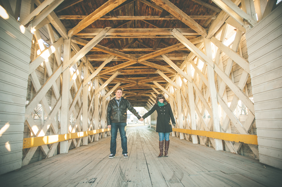 Rustic fall engagement photo of couple inside an old covered bridge